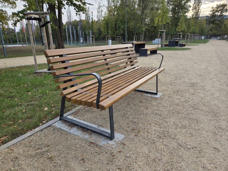 Ławka warszawska z oparciem i podłokietnikami w parku